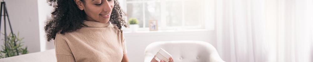 Young woman removes sample jar of cream from a marketing mail parcel.